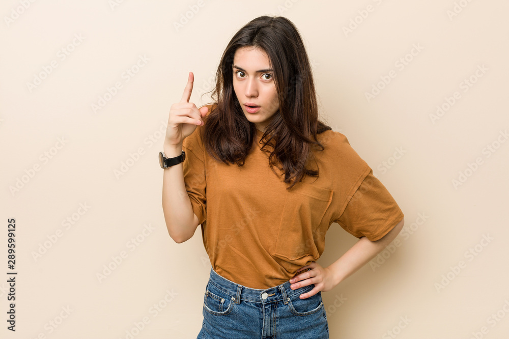 Young brunette woman against a beige background having an idea, inspiration concept. Young brunette woman against a beige background having an idea, inspiration concept.