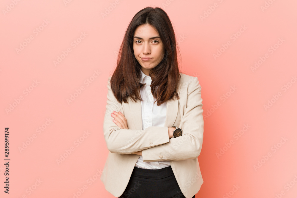 Young brunette business woman against a pink background frowning face in displeasure, keeps arms folded. Young brunette business woman against a pink background frowning face in displeasure, keeps arms folded.