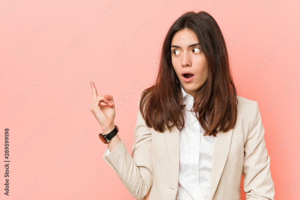 Young brunette business woman against a pink background pointing to the side Young brunette business woman against a pink background pointing to the side