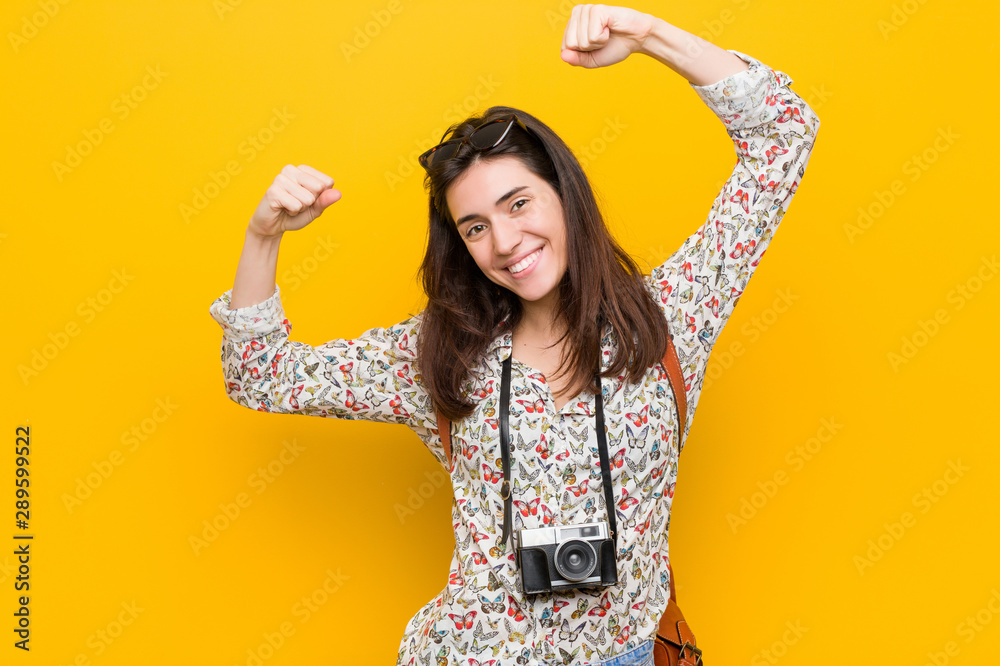 Young brunette traveler woman showing strength gesture with arms, symbol of feminine power Young brunette traveler woman showing strength gesture with arms, symbol of feminine power
