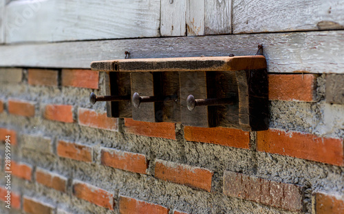 Rack on the weathered white brick wall. Old Wall Hook Rack. Hanger with metal hook on the concrete cement wall created retro loft style decoration.