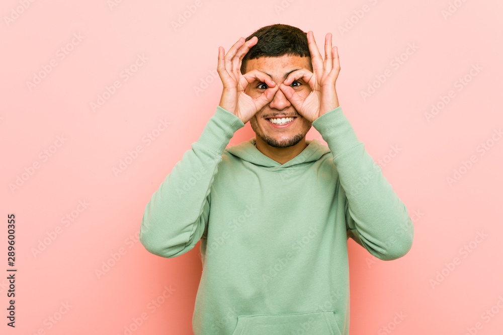 Young hispanic sport man showing okay sign over eyes Young hispanic sport man showing okay sign over eyes
