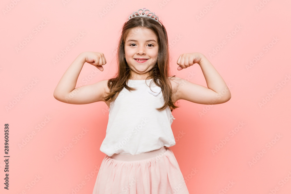 Little girl wearing a princess look showing strength gesture with arms, symbol of feminine power Little girl wearing a princess look showing strength gesture with arms, symbol of feminine power