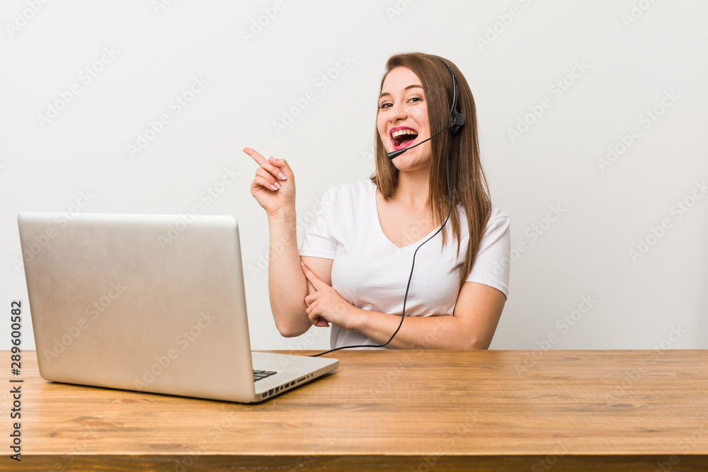 Young telemarketer woman smiling cheerfully pointing with forefinger away.