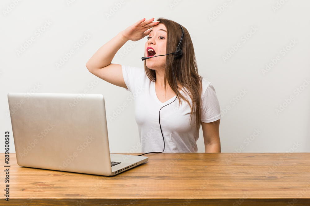 Young telemarketer woman looking far away keeping hand on forehead. Young telemarketer woman looking far away keeping hand on forehead.