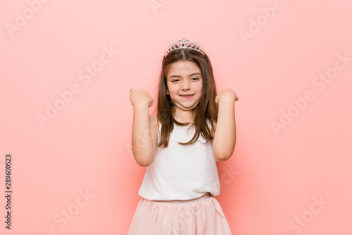 Little girl wearing a princess look cheering carefree and excited. Victory concept.