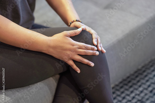 Close-up african female Leg With Painful Knees. Young african woman Feeling Joint Pain, Having Health Issues And Touching Leg With Hands. Pain In Knee. Body And Health Care Concept. 