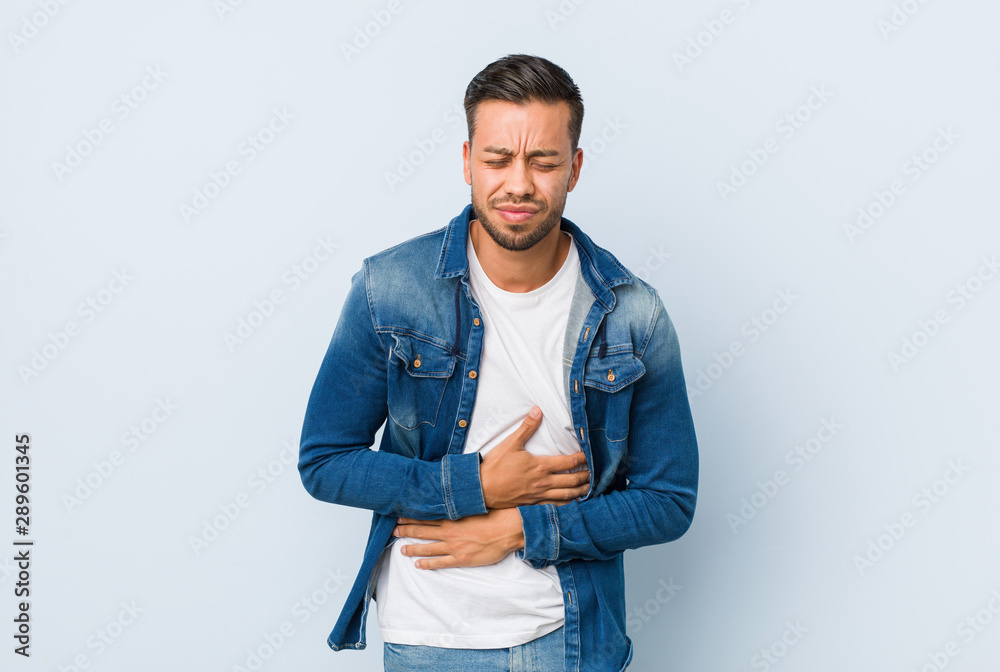Young handsome filipino man sick, suffering from stomachache, painful disease concept. Young handsome filipino man sick, suffering from stomachache, painful disease concept.