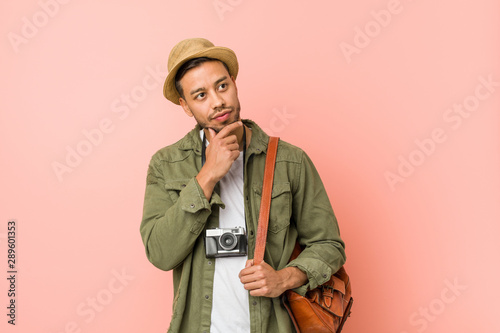 Young filipino traveler man looking sideways with doubtful and skeptical expression. © Asier
