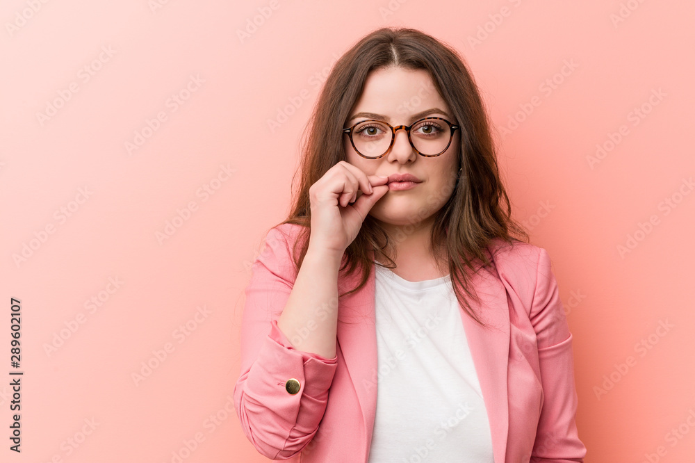 Young plus size business caucasian woman with fingers on lips keeping a secret.