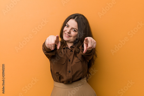 Young curvy russian woman cheerful smiles pointing to front. © Asier