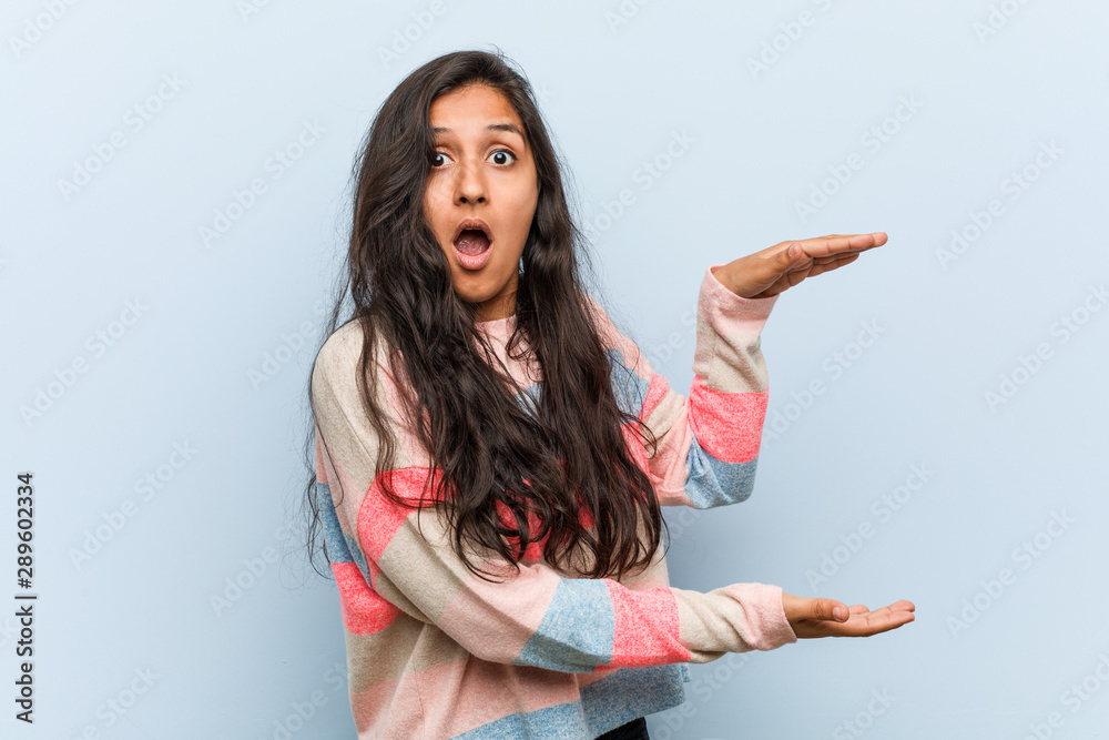 Young fashion indian woman shocked and amazed holding a copy space between hands. Young fashion indian woman shocked and amazed holding a copy space between hands.