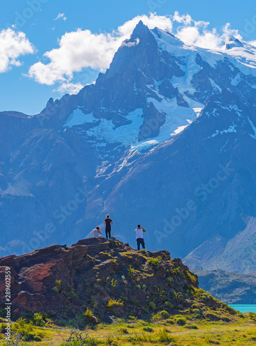 Vertical photograph of tourists looking upon the Pehoe Lake and the majestic peaks of Cuernos and Torres del Paine inside Torres del Paine national park near Puerto Natales, Patagonia, Chile.