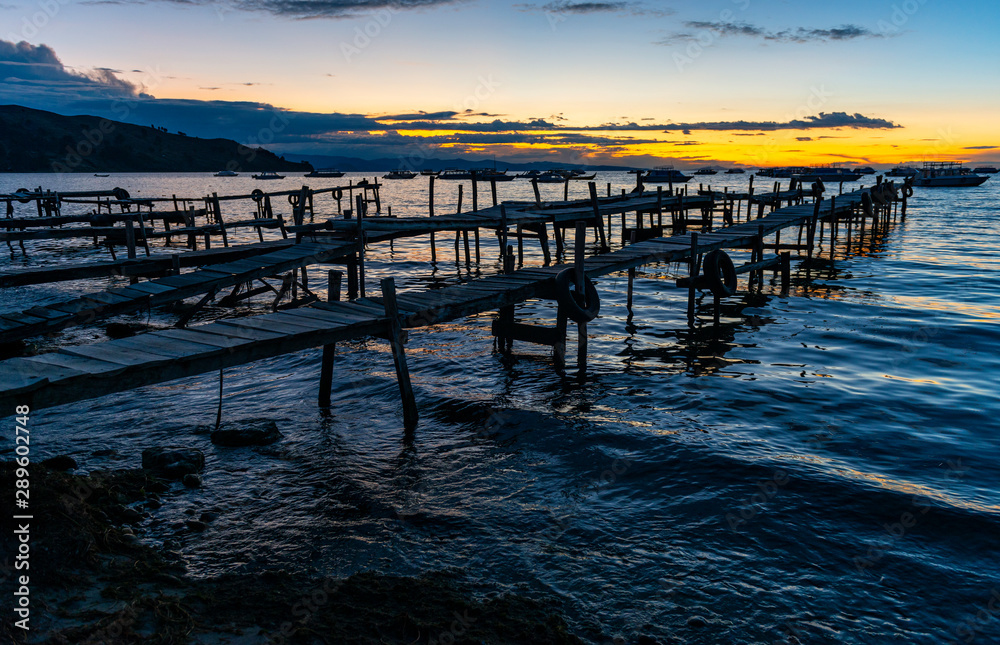 Fototapeta premium The small harbor of Copacabana with its wooden piers at sunset by the Titicaca Lake, Bolivia.