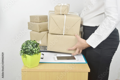 Female entrepreneur holding clipboard with check customer order and have packaging box on the side.
