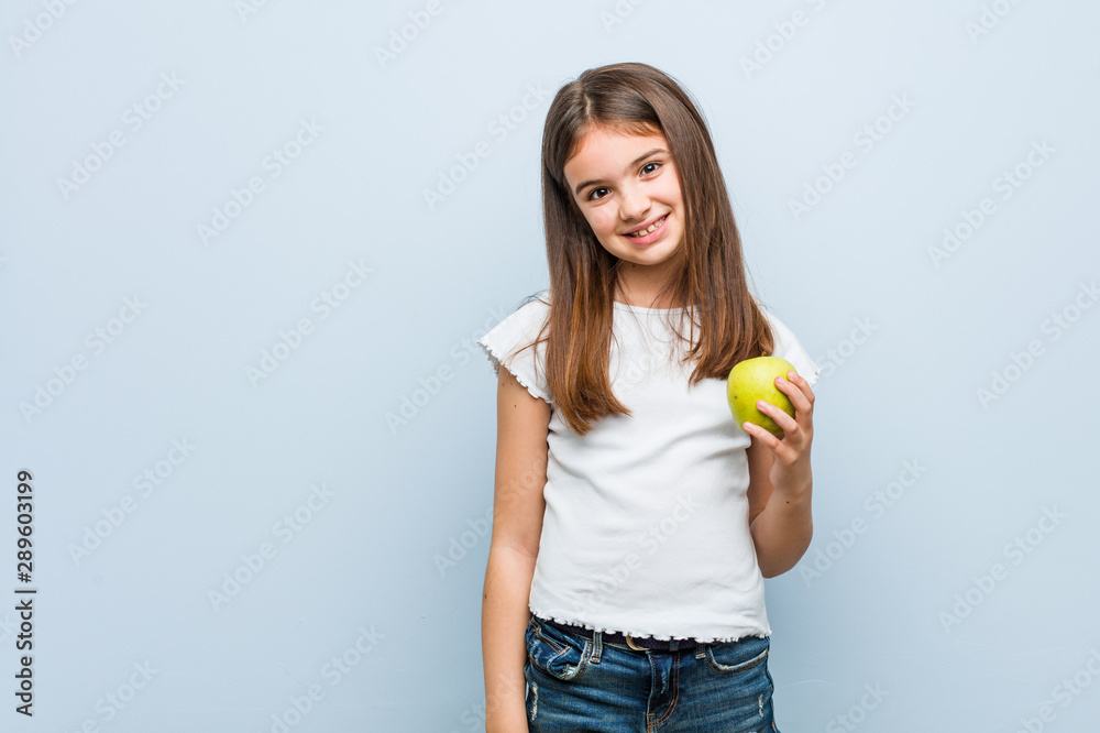 Little caucasian girl holding a green apple happy, smiling and cheerful. Little caucasian girl holding a green apple happy, smiling and cheerful.