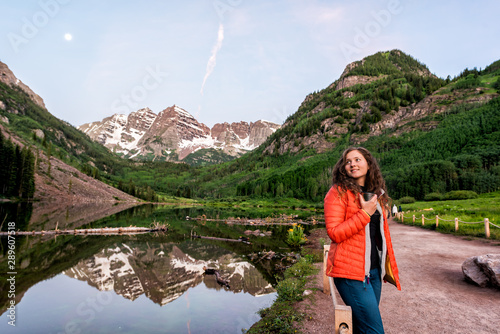 Maroon Bells in Aspen, Colorado at blue hour in July 2019 summer and moon reflection at sunrise with woman drinking coffee or tea in morning