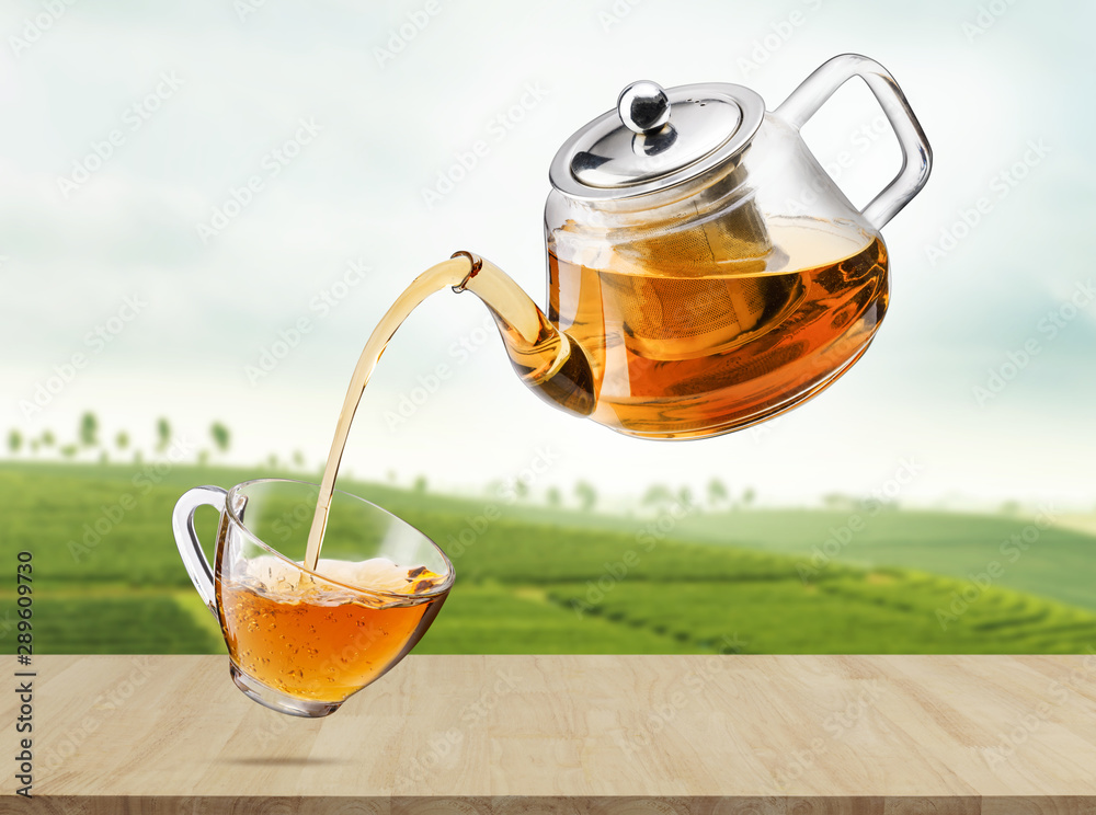Jug pouring hot tea into glass cup in the air with tea plantations, Healthy  products by organic natural ingredients concept, Empty space in studio shot  Stock-foto | Adobe Stock