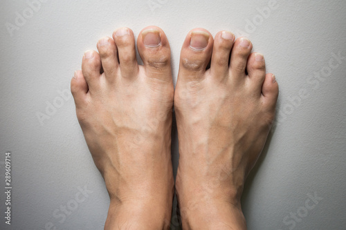 The foot and long nail toes on white concrete background. © Aonprom Photo