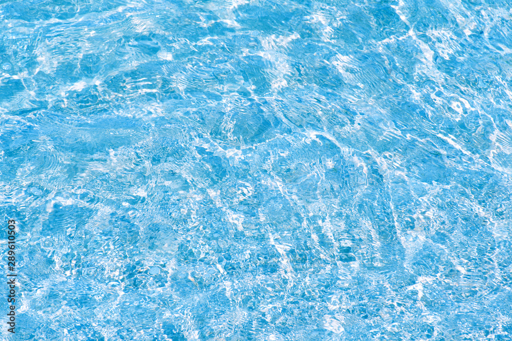 Water rippled and sunny reflections in swimming pool surface background.