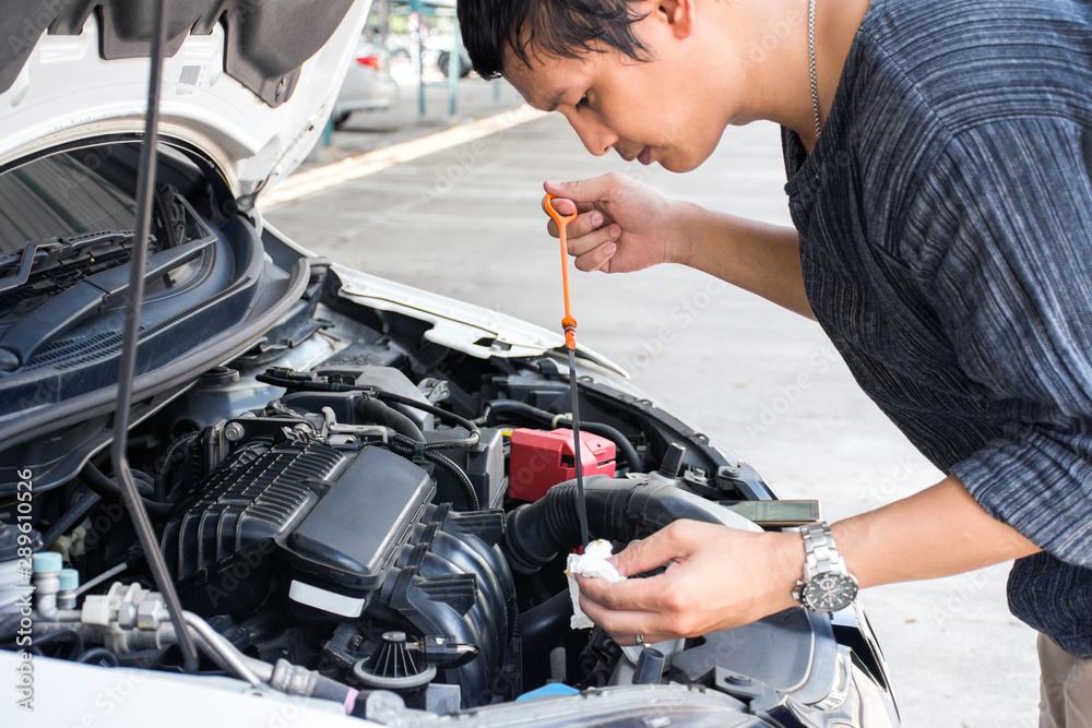 Man or auto mechanic worker checking the car engine oil and maintenance before traveling for safety.