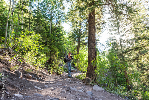 Maroon Bells crater lake trail in Aspen  Colorado with forest footpath and man taking picture of porcupine wildlife wild animal