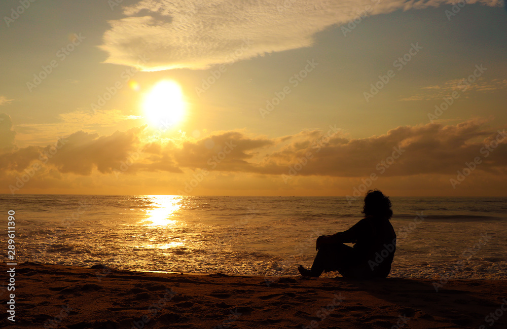  Indian woman meditating on morning sunrise beach