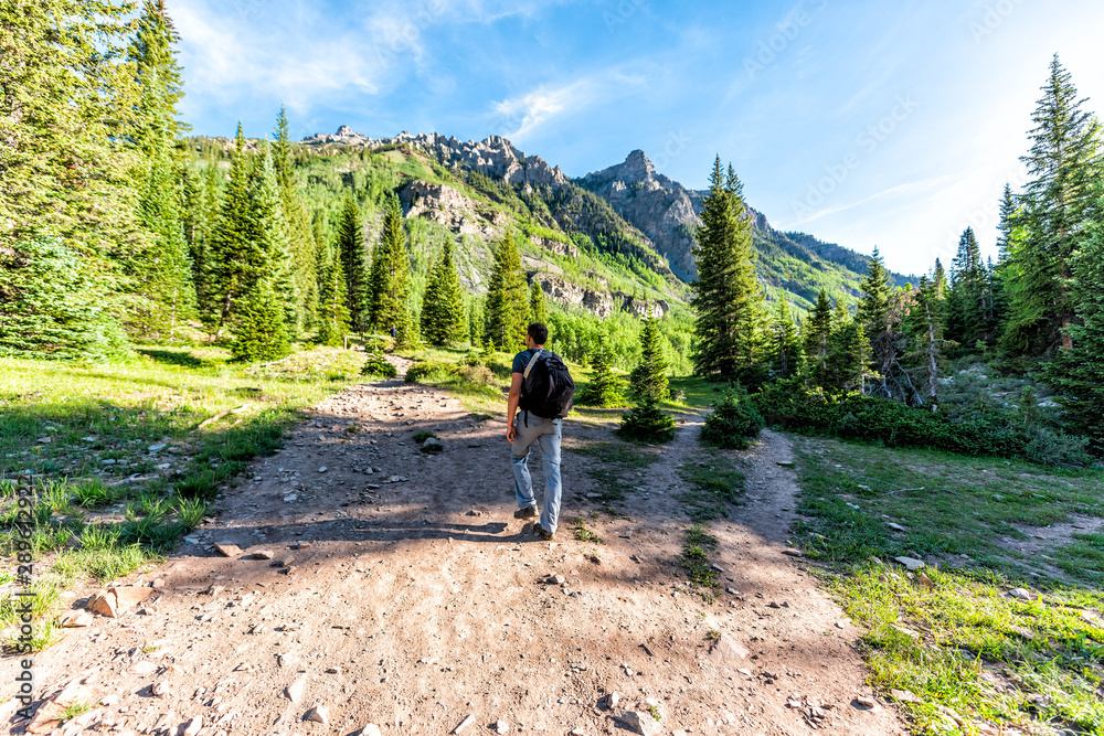 Maroon Bells trail view in Aspen, Colorado with tourist man backpack hiker walking in July 2019 summer on path road wide angle view