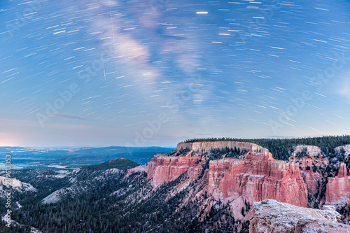 Night sky with star trails motion in Bryce Canyon National Park in Utah showing red canyons landscape  milky way and blue color at Paria view