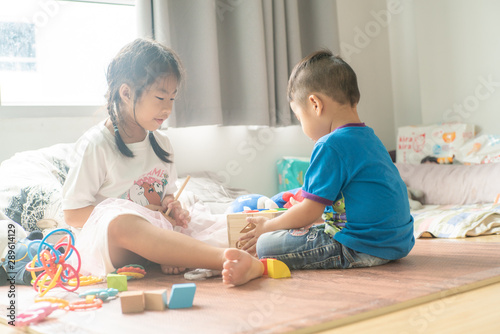 Asian cute little children playing with toy box while sitting on wood floor