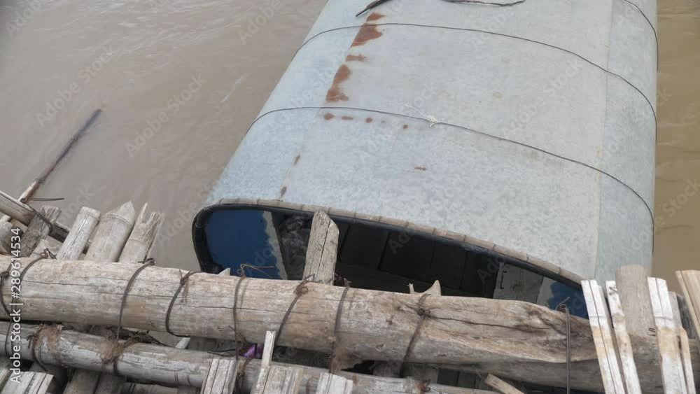 close up of a small fishing boat gets stuck under the bamboo bridge after the river rising during the night close up of a small fishing boat gets stuck under the bamboo bridge after the river rising during the night