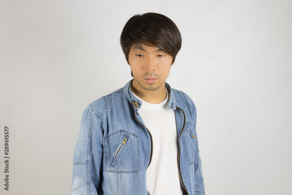 Young Asian Man in Jeans or Denim Jacket Looking Below at Front View Young Asian Man in Jeans or Denim Jacket Looking Below at Front View