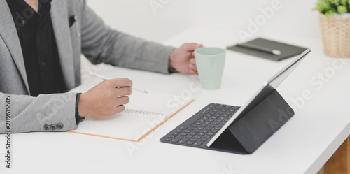 Young professional businessman working on his upcoming project while holding coffee cup