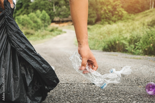 The volunteer picking up a bottle plastic in to a bin bag for cleaning, volunteering concept. Environmental pollution and Ecological problem. photo