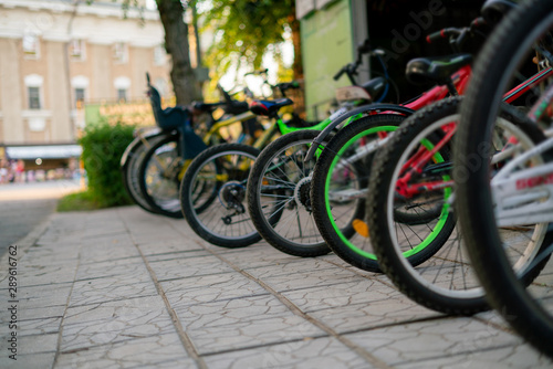 row of many bicycles parked on the public city rent in the park on a summer season, weekend activitiy.