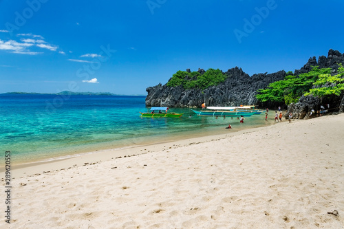 Unrecognisable people playing by the Banca boats on Lahus Island beach in the municipality of Caramoan, Camarines Sur Province, Luzon in the Philippines, region for Survivor TV shows filming.