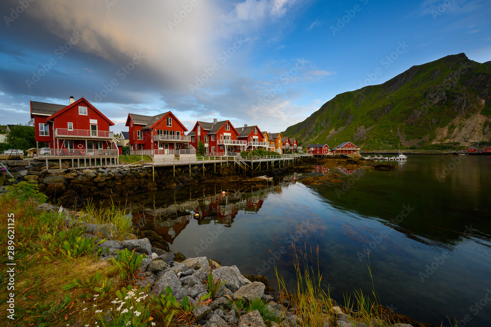 Beautiful waterfront house reflecting the water Evening and twilight sky at ballstad city, lofoten island in northern Norway. Rorbuer is the traditional home of Norwegian fishermen.