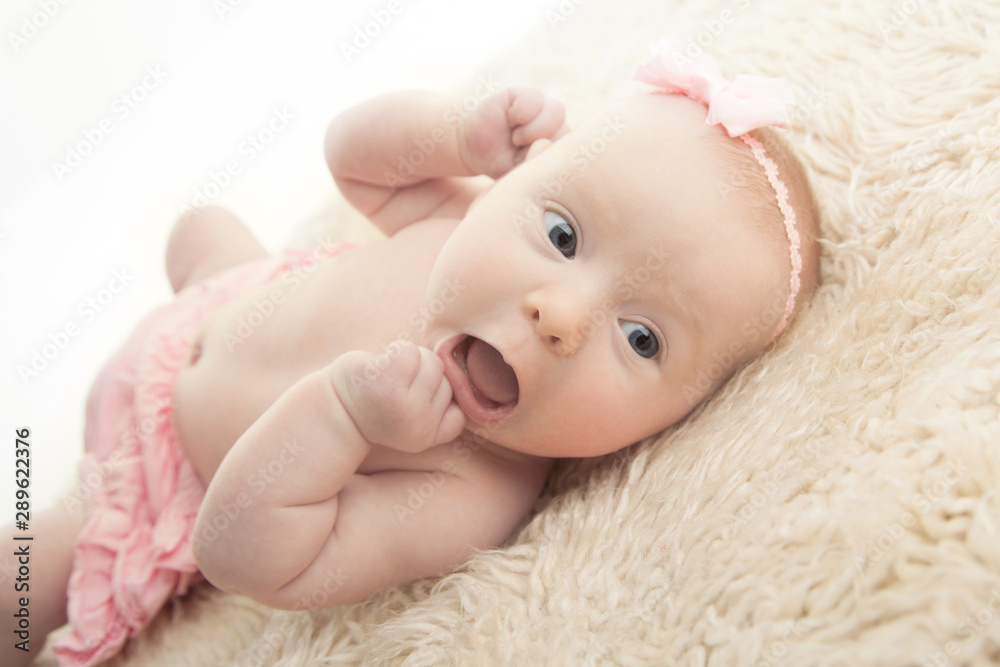 Baby girl lying on back with mouth open, chewing fingers Baby girl lying on back with mouth open, chewing fingers