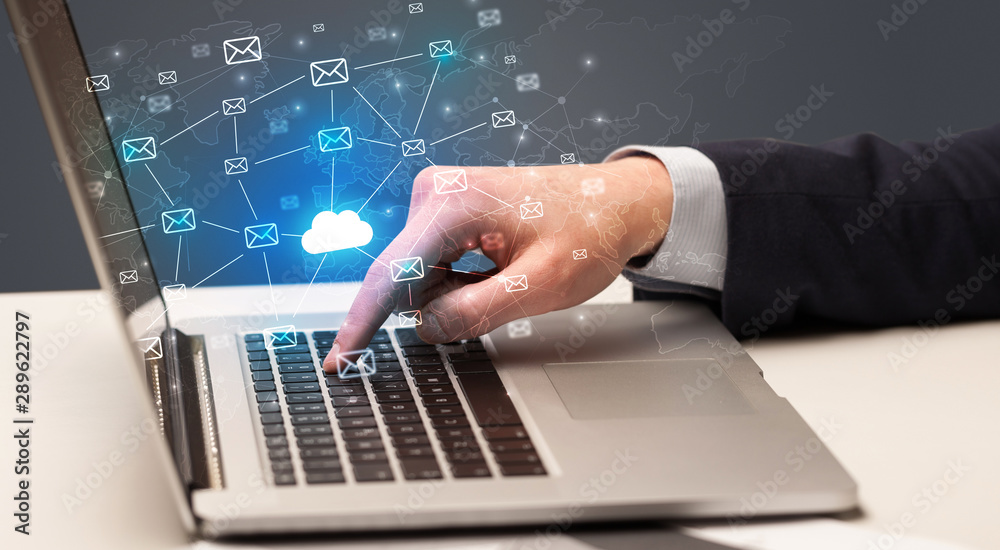 Businessman hand sending a bunch of messages on laptop with cloud computing concept Businessman hand sending a bunch of messages on laptop with cloud computing concept