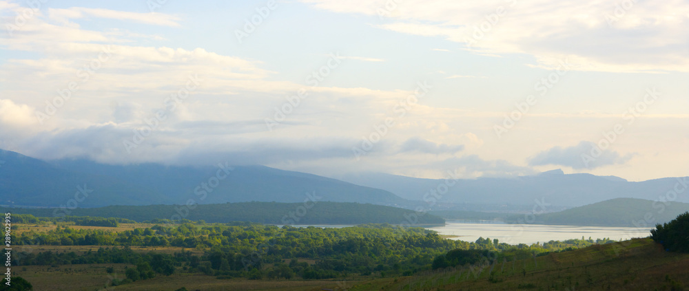 Lake in valley among foggy mountains