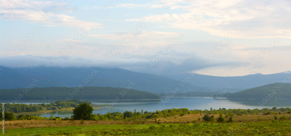 Obraz premium Lake in valley among foggy mountains