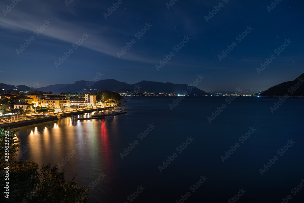 Famous big European lake at night. Lake Maggiore with the city of Maccagno, in the background the lights of the stretch of coast between the cities of Germignaga and Stresa, Italy