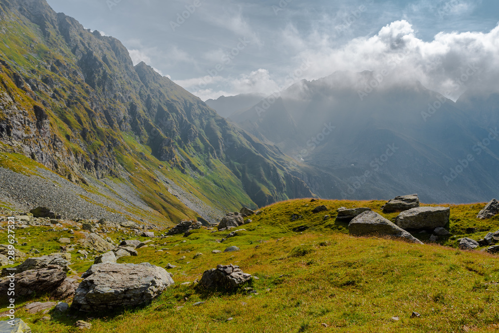 Wild mountain landscape with clouds and sunbeams. Fagaras Mountains, Romania