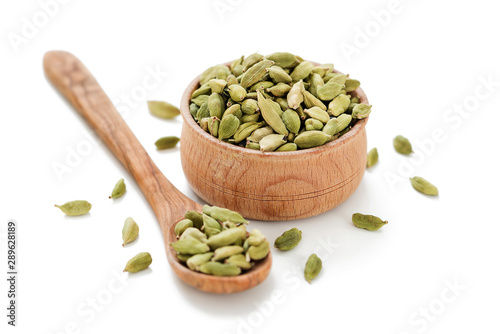 Cardamom pods in a wooden bowl isolated on white background.