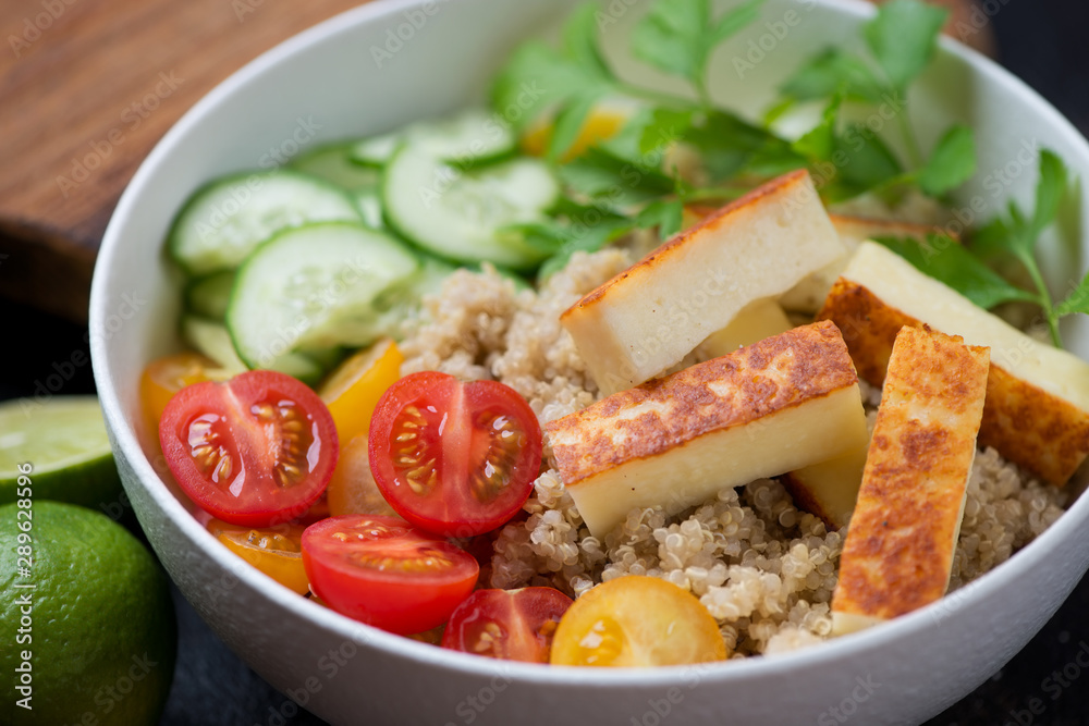Bowl with quinoa, fried cheese, cherry tomatoes, cucumber and parsley, close-up, selective focus Bowl with quinoa, fried cheese, cherry tomatoes, cucumber and parsley, close-up, selective focus