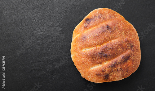 Fresh hot focaccia bread (pita) on black stone background.