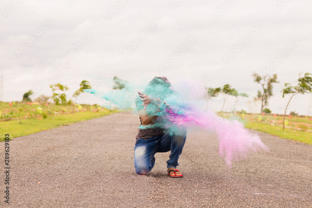 Fototapeta Concept of holi festival, Man exploding colorful powders in hands on road.