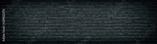Widescreen black brick wall texture. Aged rough masonry background. Dark brickwork wide back wallpapers