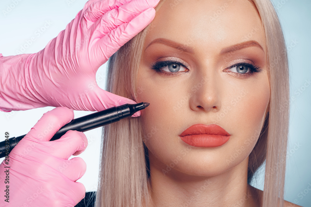 Woman face and doctor hands with pencil. Plastic surgery concept Woman face and doctor hands with pencil. Plastic surgery concept