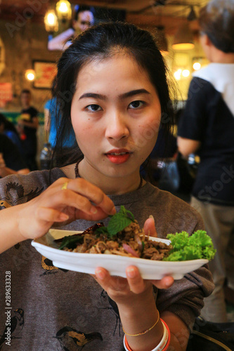 Girl in a somtum Papaya salad  shop.With on the face shows a delicious spicy.